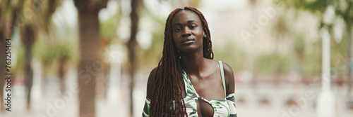 Gorgeous woman with African braids wearing walks down the street. Stylish girl walking on the park  Panorama