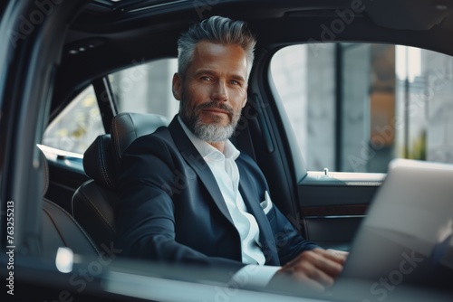 Businessman with laptop in luxury car interior, modern entrepreneur © Iona