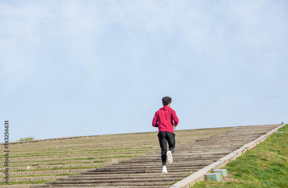 Back view of unrecognizable young man running up a wooden stairs outdoors Back view of unrecognizable young man running up a wooden stairs outdoors