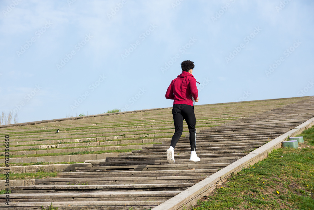 Back view of unrecognizable young man running up a wooden stairs outdoors Back view of unrecognizable young man running up a wooden stairs outdoors