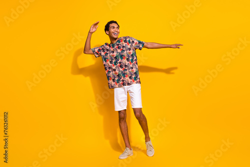 Full body length photo of having fun young man tourist student spend his free time outdoors dancing isolated on yellow color background #763261012