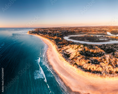 Aerial View over a long sandy stretch of beach during sunset, with blue water waves rolling onto shore, Port Noarlunga, South Australia, Australia. photo