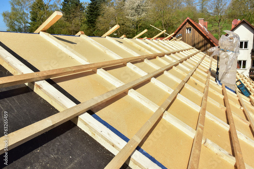Dachdecker beim Verlegen und befestigen der Dachlatten eines Steildachs auf der Holzfaserdämmung für die Eindeckung mit Ziegeln photo