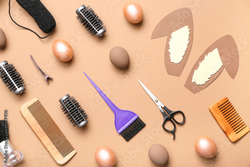 Hairdressing accessories with paper bunny ears and Easter eggs on light brown background