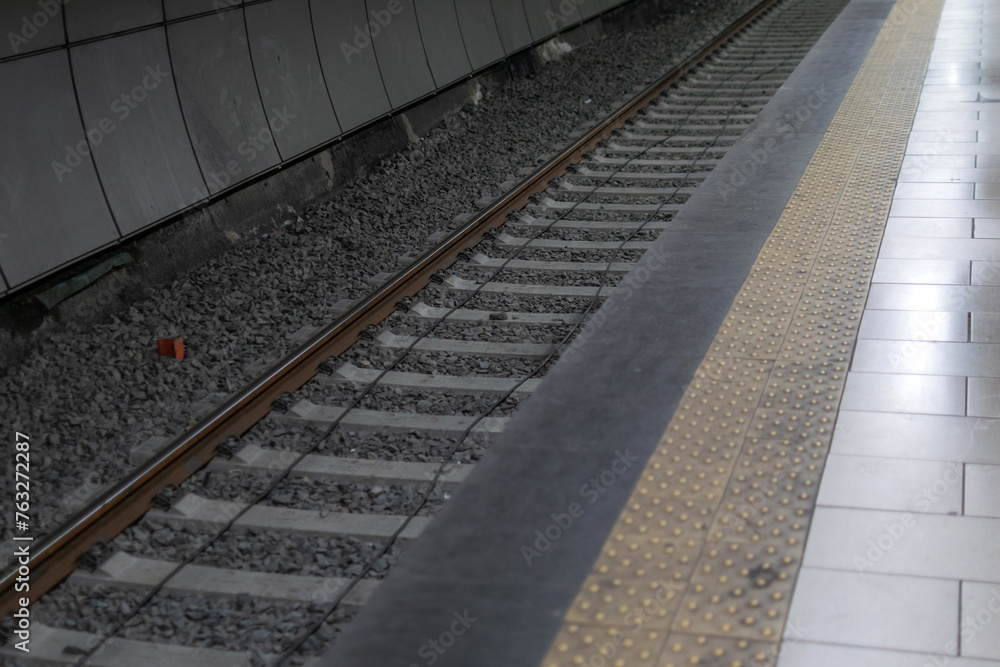 Railway metal rails and concrete sleepers for a metro train on gray gravel inside the underground metro station