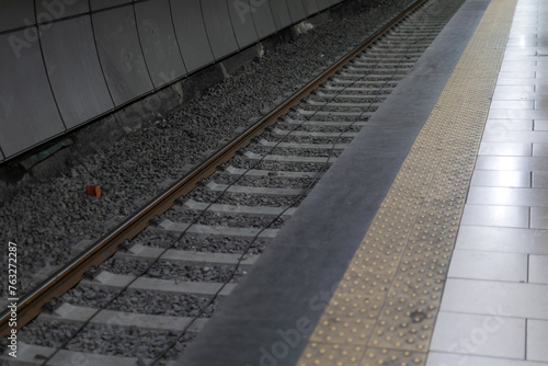 Railway metal rails and concrete sleepers for a metro train on gray gravel inside the underground metro station