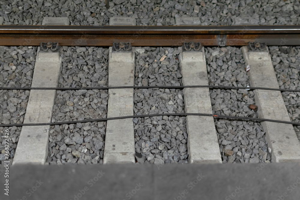 Close-up - railway track metal rails on concrete sleepers, lie on fine gray gravel