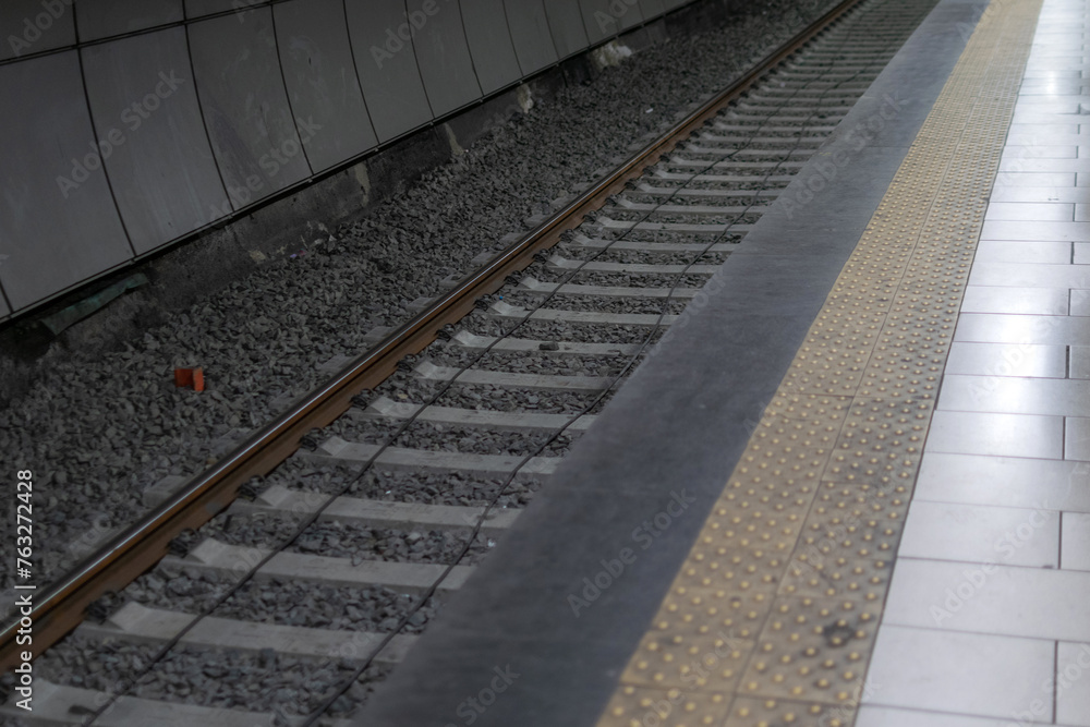 Railway metal rails and concrete sleepers for a metro train on gray gravel inside the underground metro station