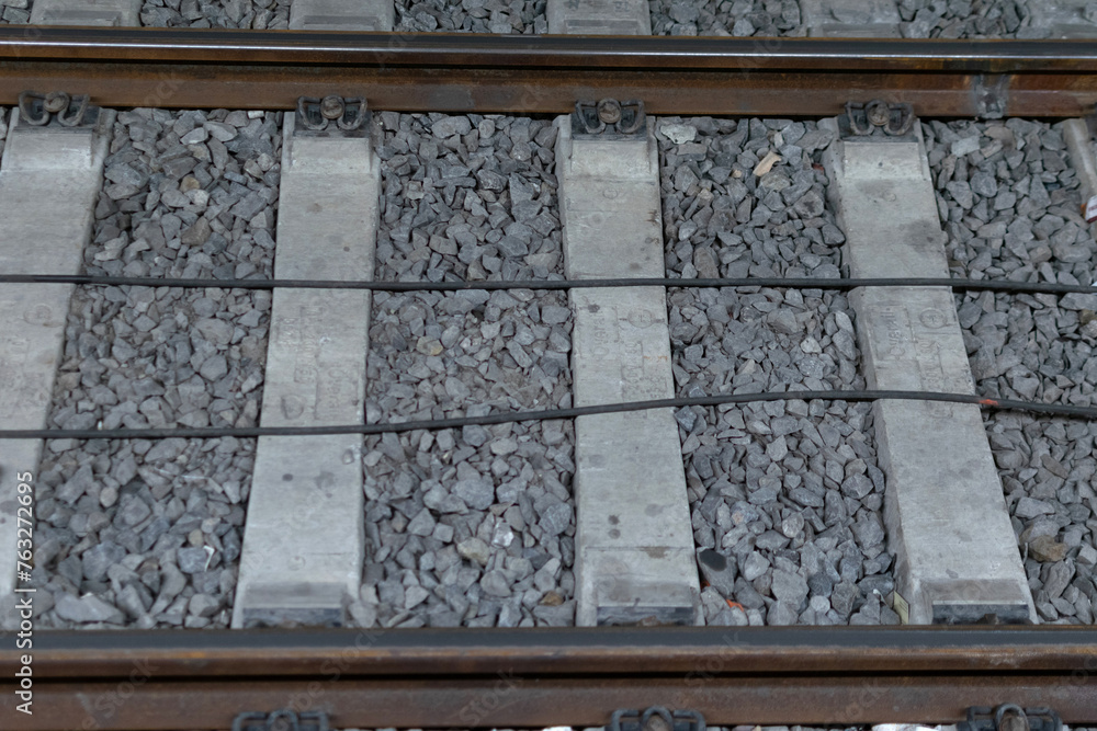 Close-up - railway track metal rails on concrete sleepers, lie on fine gray gravel