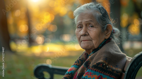 Portrait, elderly Mexican and woman sitting in park. Senior, female and mental health concept. Sadness, longing and thoughtful for mental health and reminiscing with beautiful blurry background.