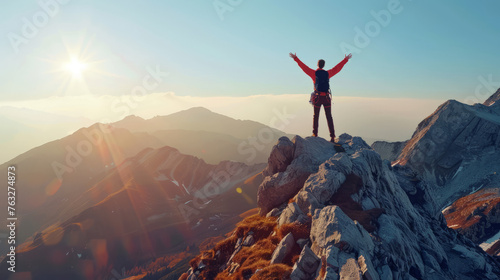 happy man raising his arms jumps to the top of the mountain - a successful mountain climber celebrates his success on the cliff