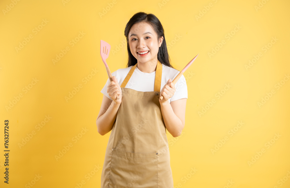 Portrait of Asian housewife girl posing on yellow background Portrait of Asian housewife girl posing on yellow background