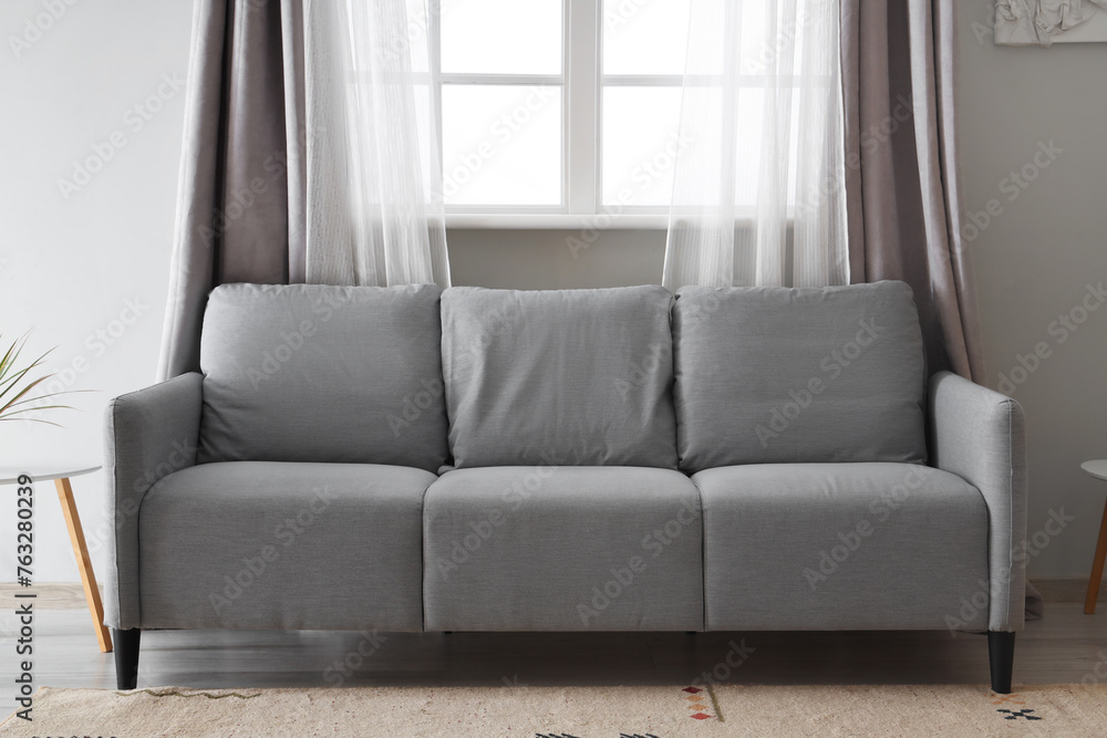 Fototapeta premium Grey sofa near window in living room