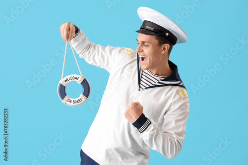 Fotografie Young sailor with small ring buoy on blue background