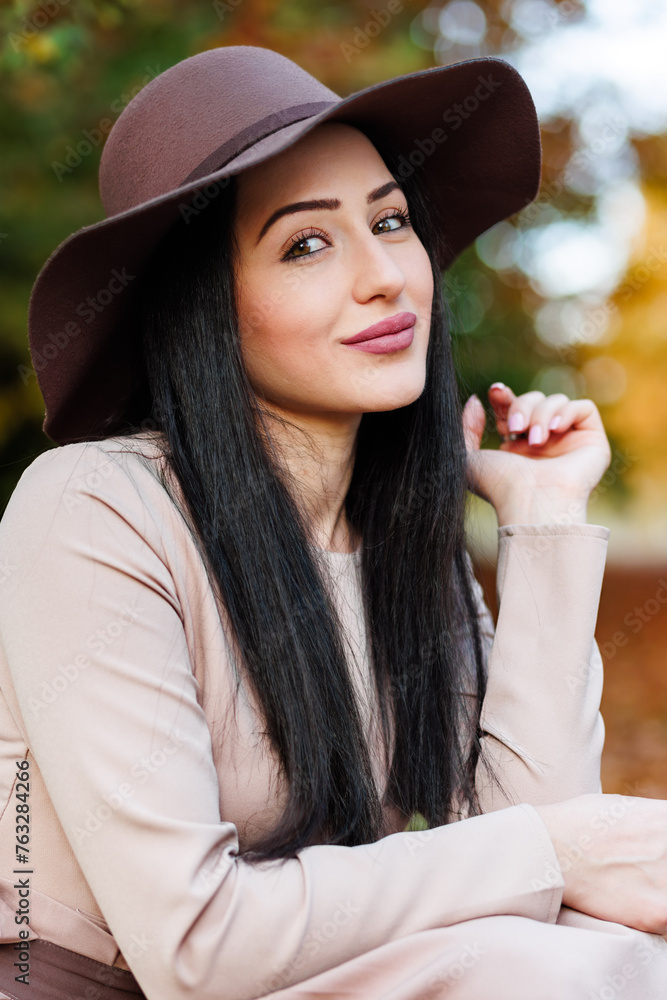 Autumn ttire. Young woman in a stylish hat showcasing a modern outfit against a backdrop of fall leaves