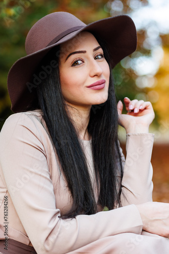 Obraz na płótnie Autumn ttire. Young woman in a stylish hat showcasing a modern outfit against a backdrop of fall leaves w salonie