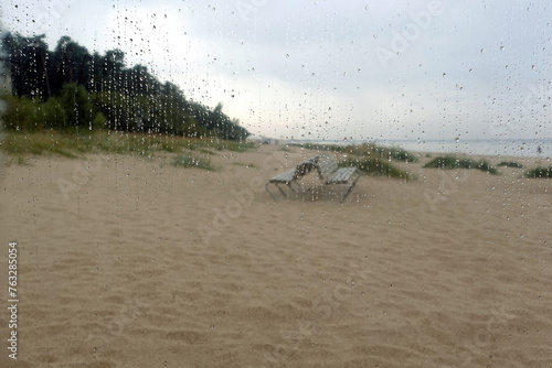 Rainy day on empty sandy beach in Jurmala resort seacoast in low season defocused view from the window with rain drops