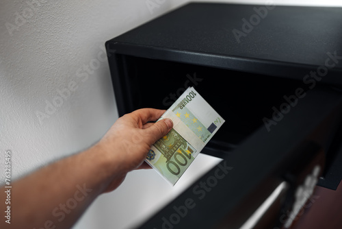 Man puts or takes euro banknotes from a safe.