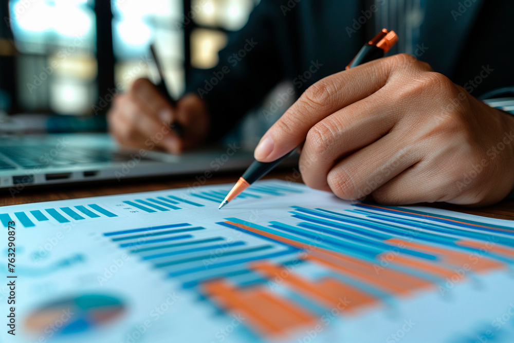 Printed charts of economic growth on the table. Person writing on sheet of paper with retro pen. Printed charts of economic growth on the table. Person writing on sheet of paper with retro pen.