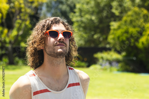 A young Caucasian man gazes upwards, sporting orange sunglasses with copy space at home outdoors