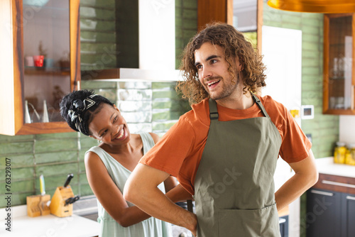 A diverse couple tying apron for cooking together in the kitchen