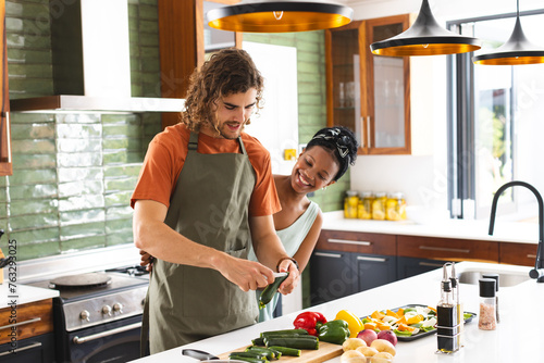 A diverse couple is preparing food together in modern kitchen