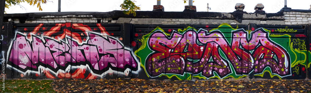 The old wall decorated with paint stains in the style of street art culture. Colorful background of full graffiti painting artwork with bright aerosol outlines on wall. Colored background texture The old wall decorated with paint stains in the style of street art culture. Colorful background of full graffiti painting artwork with bright aerosol outlines on wall. Colored background texture