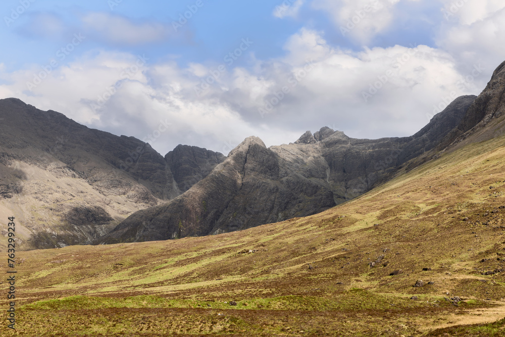 Fototapeta premium The rugged grandeur of the Cuillin Hills looms over the Fairy Pools, offering a majestic view against the stark beauty of Isle of Skye famous landscapes