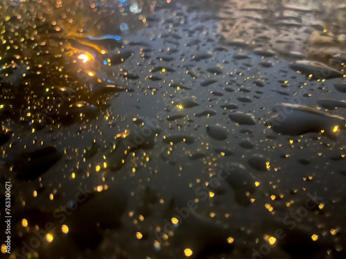Closeup of water drops with light reflections on black surface