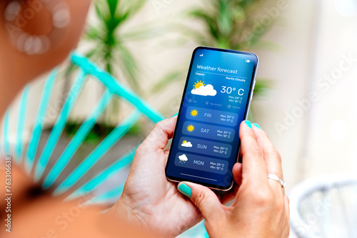 Bilde på lerret Woman outdoors checking the weather forecast on an app on her mobile phone