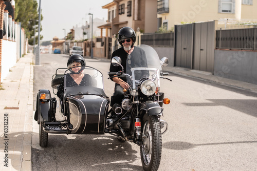 a mature senior couple aged 60 or older prepare for a sidecar ride