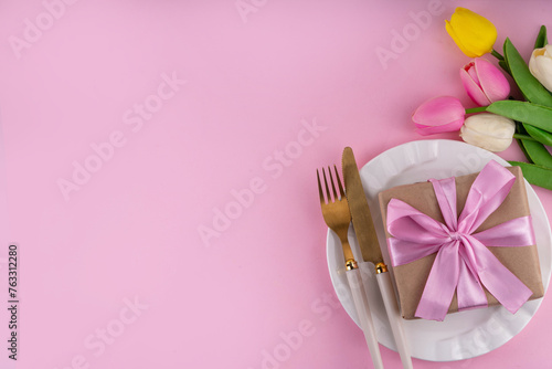 Mother day table setting background. Pink Mother\'s day border flat lay for brunch, lunch, dinner menu, invitation mockup. Beautiful table setting with golden cutlery, plate, tulip flowers and gift box