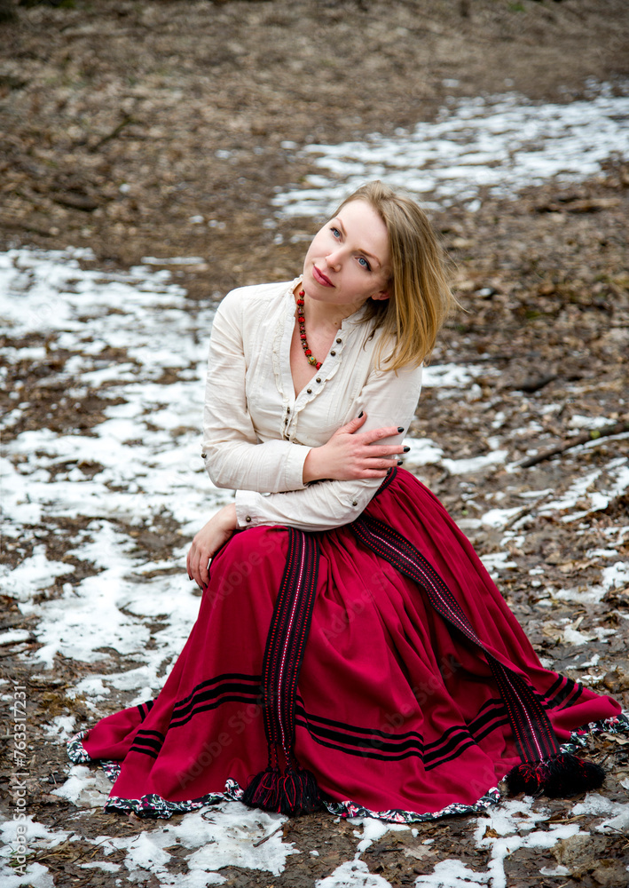 romantic single beautiful blonde girl in ukrainian traditional clothes and red skirt and boots sitting in empty winter field with snow romantic single beautiful blonde girl in ukrainian traditional clothes and red skirt and boots sitting in empty winter field with snow