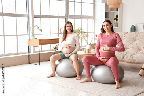 Pregnant female friends training on fitballs at home