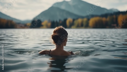 A woman swims in a lake with a mountain in the background photo