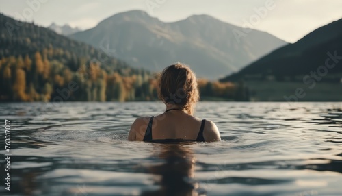 A woman swims in a lake with a mountain in the background