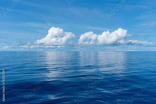 Beautiful blue sky, with fluffy clouds over the calm Pacific Ocean. 