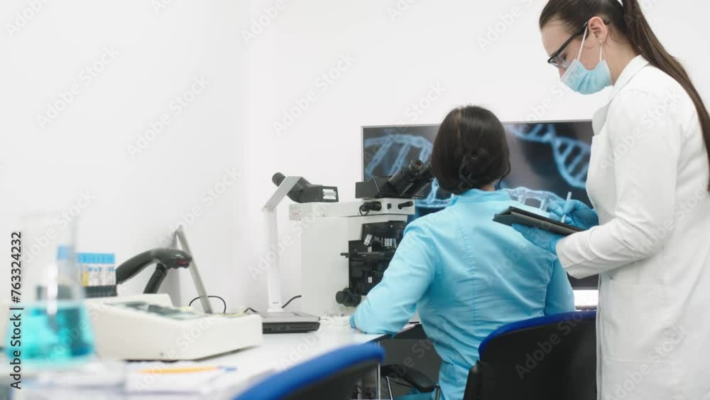 Medical science laboratory with diverse team of professional biotechnology scientists developing drugs, female biochemist working on computer demonstrating gene therapy interface. Medical science laboratory with diverse team of professional biotechnology scientists developing drugs, female biochemist working on computer demonstrating gene therapy interface.