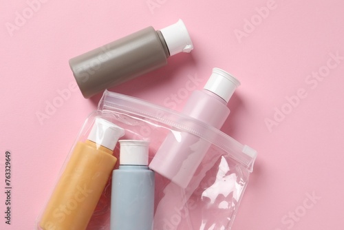 Plastic bag with cosmetic travel kit on pink background, flat lay. Bath accessories