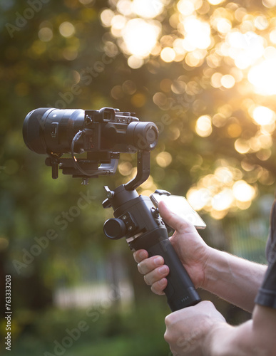 Man holding gimbal with sunset view. An unidentified person, recording with a camera on a gimbal.
