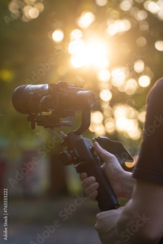 Man holding gimbal with sunset view. An unidentified person, recording with a camera on a gimbal.
