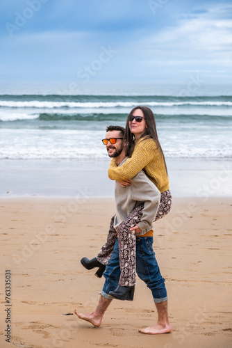 A young couple playing in the beach in winter