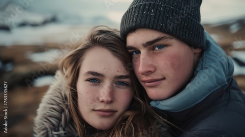 Close-up portrait of a young couple with striking blue eyes and freckles, wrapped in a cozy blanket with a snowy background, conveying intimacy and warmth. © mashimara