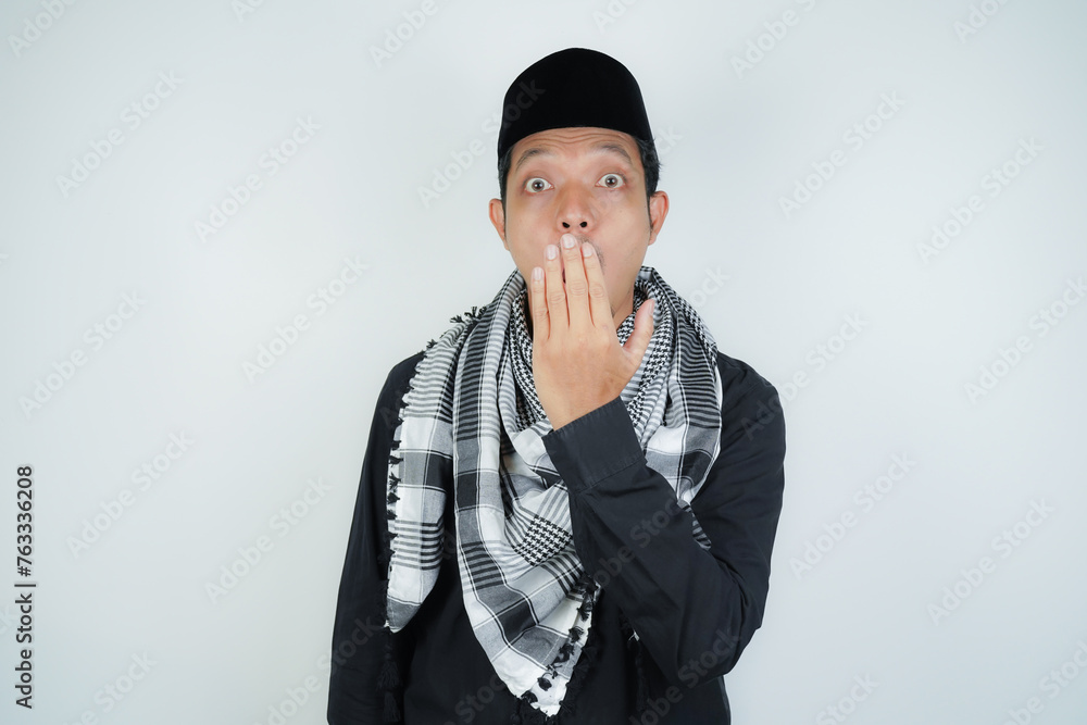 asian muslim man covering his mouth with hand or bad breath, wearing Arab turban sorban on isolated background asian muslim man covering his mouth with hand or bad breath, wearing Arab turban sorban on isolated background