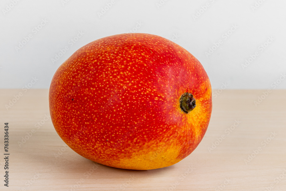A ripe sweet red mango on a wooden table A ripe sweet red mango on a wooden table