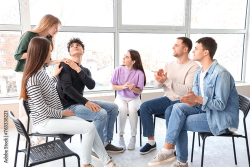 Young people calming man at group therapy session