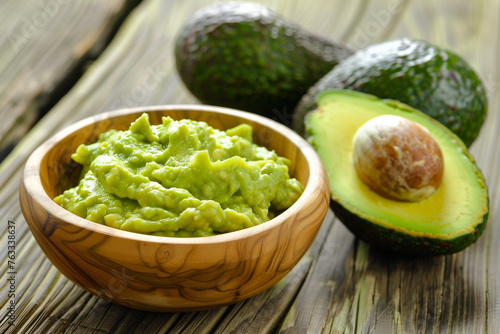 Halved avocado and guacamole in wooden bowl for healthy food concepts. photo