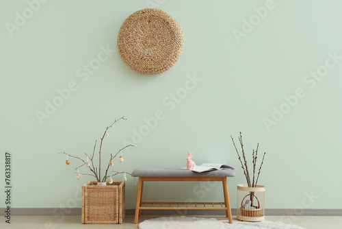 Interior of room with soft bench, tree branches and Easter eggs