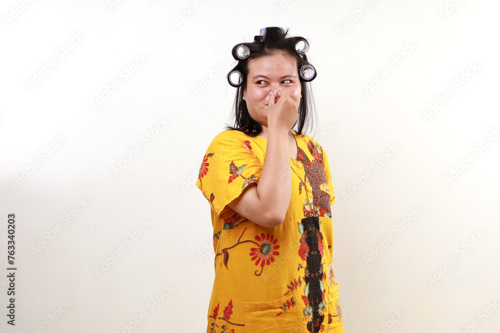 Asian housewife covering her nose while looking sideways. Bad smell concept Asian housewife covering her nose while looking sideways. Bad smell concept