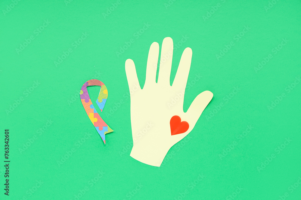 Obraz premium Paper hand, heart and awareness ribbon on green background. Concept of autistic disorder